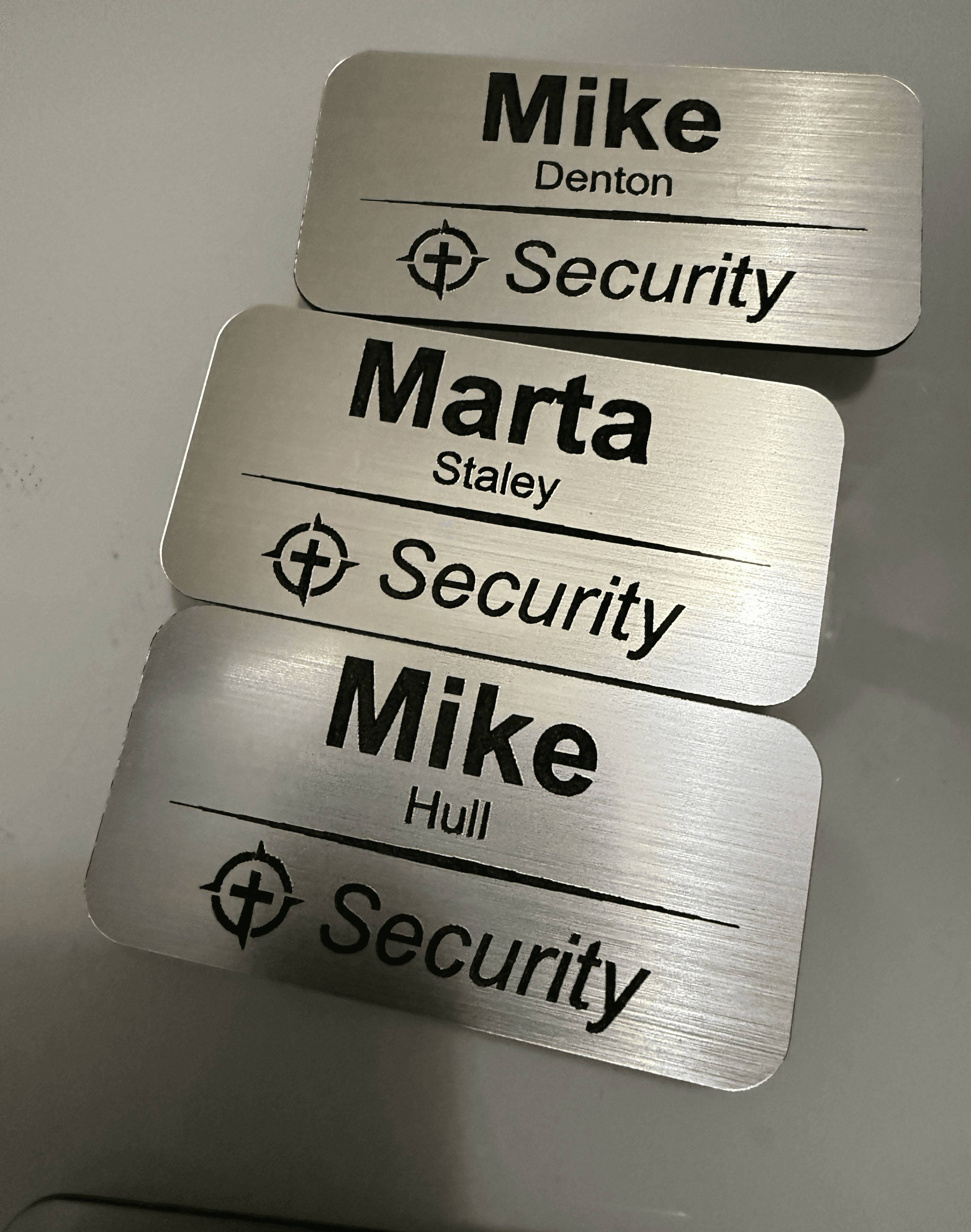 Three brushed metal security name tags for Mike Denton, Marta Staley, and Mike Hull.