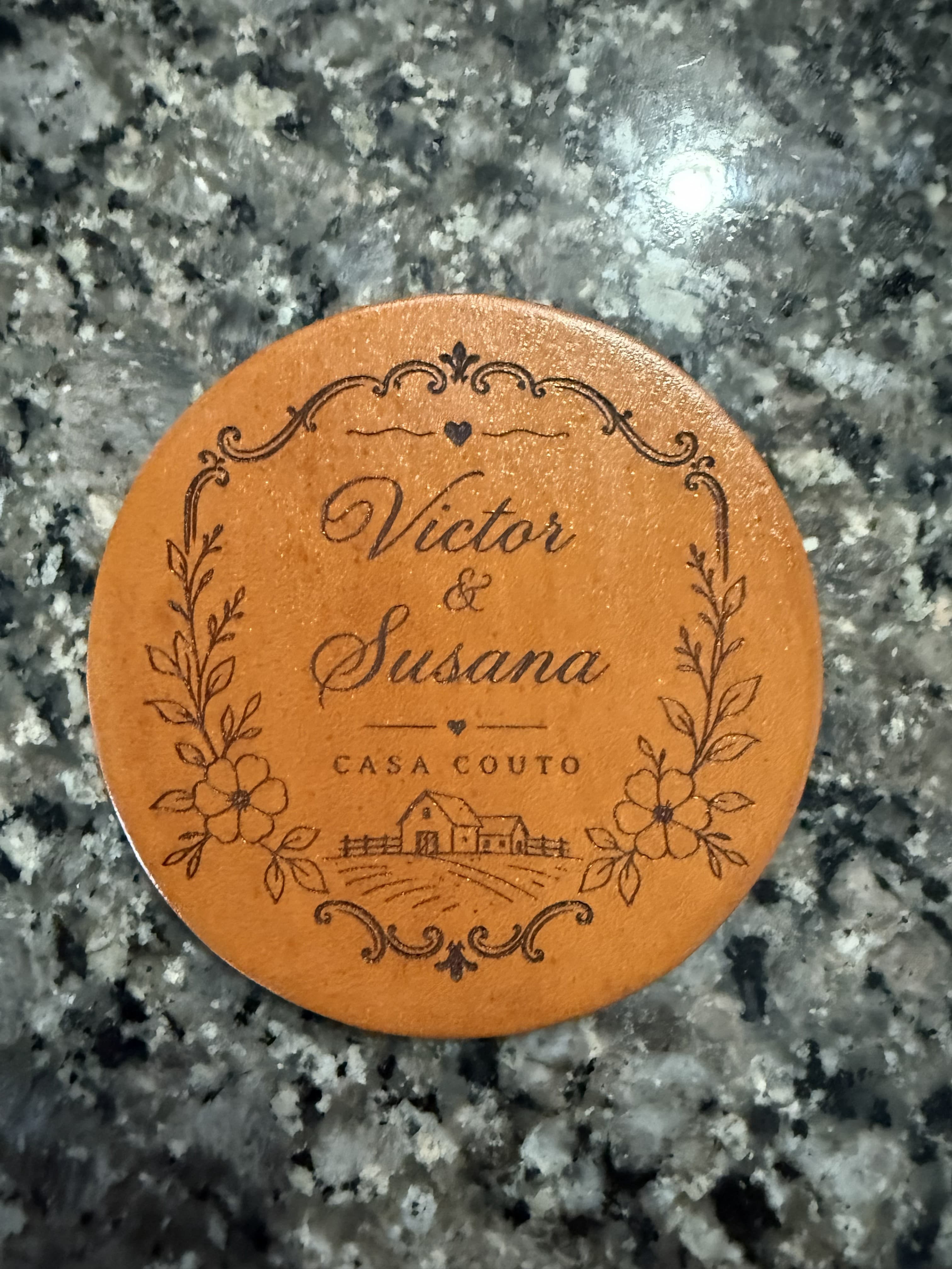 Engraved leather coaster with Victor and Susana, Casa Couto, floral borders, and a farmhouse.